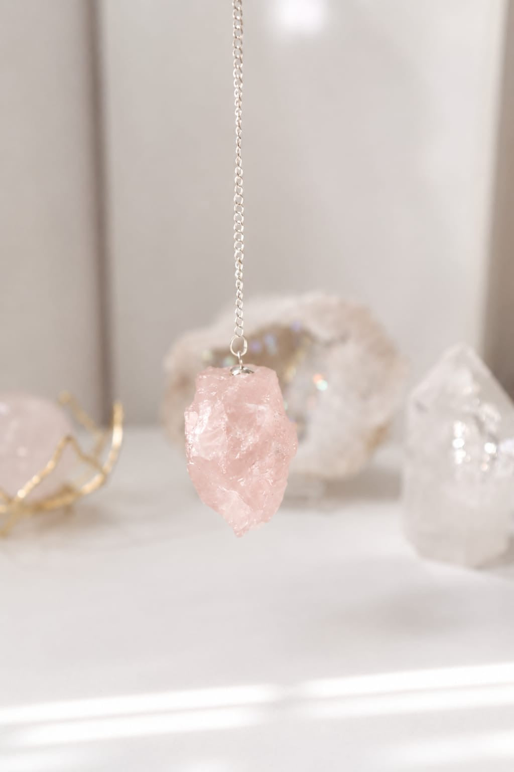 Péndulo de cuarzo rosa en bruto con cadena plateada