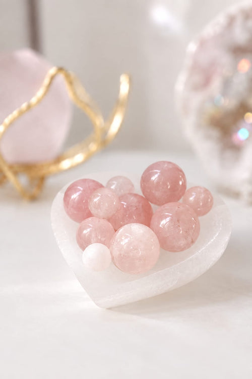 Mini esferas de cuarzo rosa pulidas en una bandeja con forma de corazón